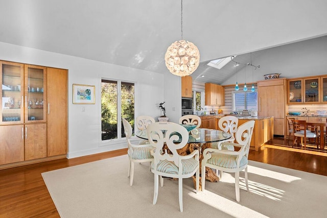 dining room with a skylight, high vaulted ceiling, and wood finished floors