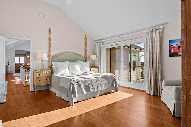 bedroom featuring access to exterior, high vaulted ceiling, and wood finished floors