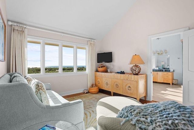 bedroom with light wood-style floors, lofted ceiling, and baseboards