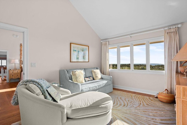 living room featuring high vaulted ceiling, baseboards, and wood finished floors