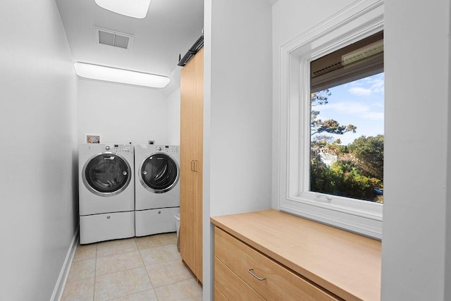 clothes washing area featuring laundry area, a barn door, light tile patterned floors, visible vents, and washer and dryer