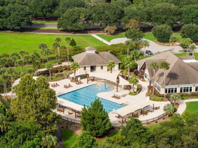 community pool with a patio, a lawn, and fence