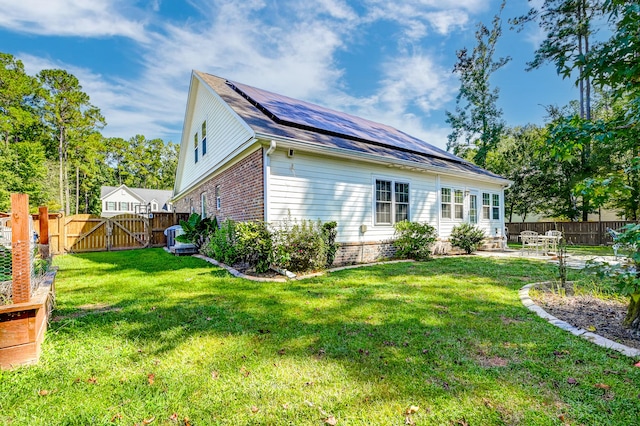 rear view of property with solar panels and a yard