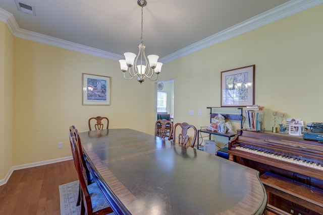 dining area with a notable chandelier, crown molding, and hardwood / wood-style flooring