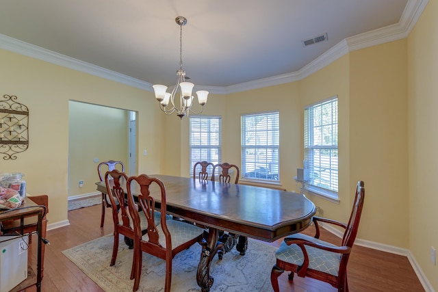 dining room with a notable chandelier, hardwood / wood-style floors, and crown molding