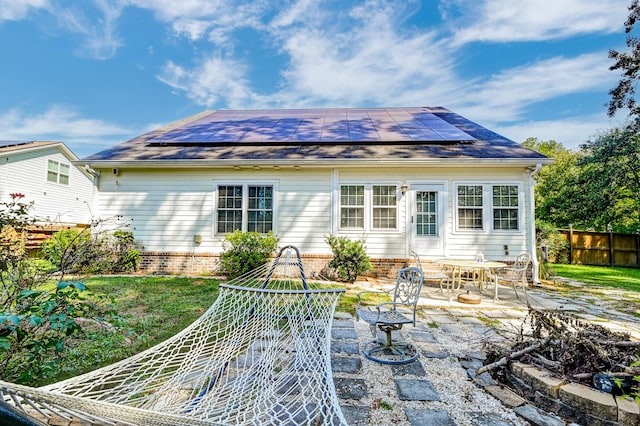 rear view of house featuring a patio, a lawn, solar panels, and a fire pit