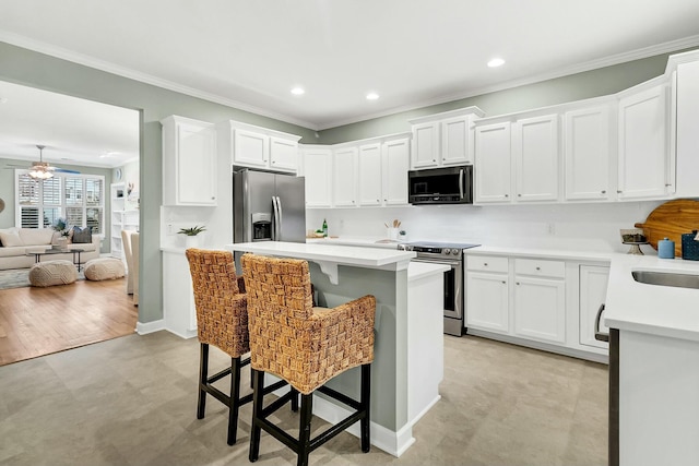 kitchen featuring white cabinets, a kitchen breakfast bar, ceiling fan, and stainless steel appliances