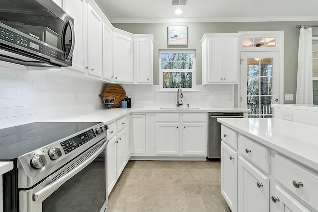 kitchen featuring white cabinets, sink, ornamental molding, tasteful backsplash, and stainless steel appliances