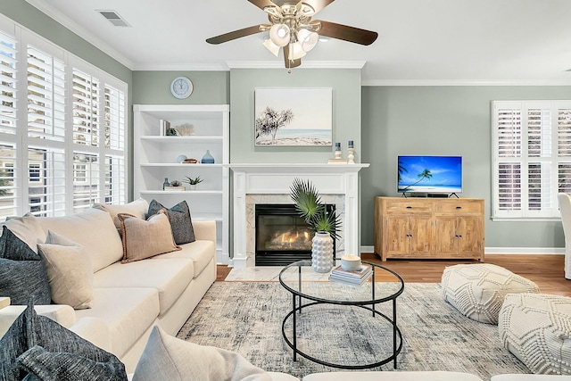 living room featuring ceiling fan, light wood-type flooring, and ornamental molding