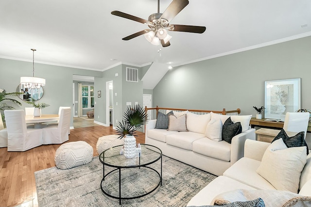 living room with ceiling fan with notable chandelier, light hardwood / wood-style floors, and ornamental molding