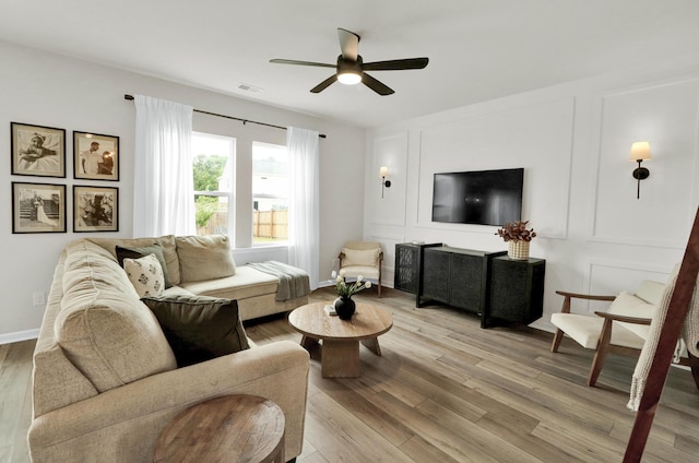 living room with a ceiling fan, light wood finished floors, and baseboards