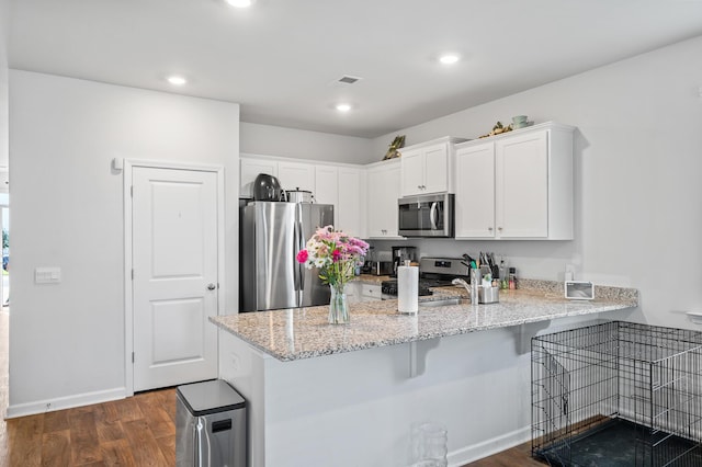 1014 Peridote Way, Ladson, SC 29456 - kitchen with stainless steel appliances, a peninsula, white cabinets, dark wood-style floors, and a breakfast bar area