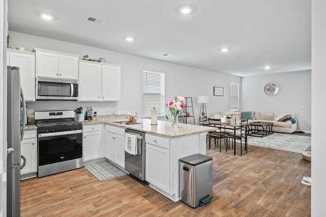 1014 Peridote Way, Ladson, SC 29456 - kitchen with stainless steel appliances, a sink, light wood-style floors, a peninsula, and white cabinetry