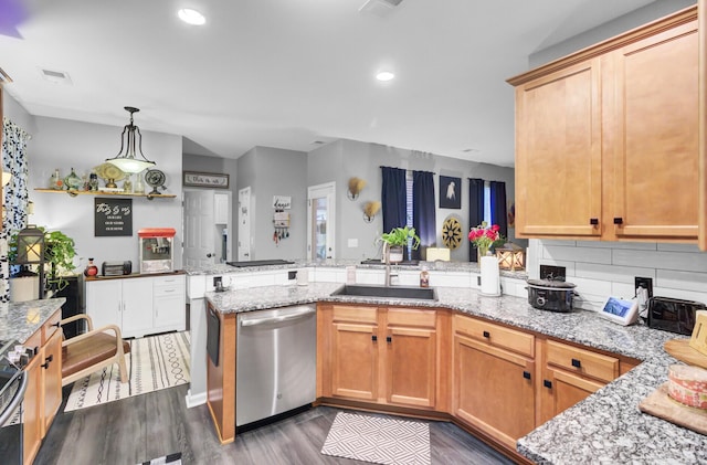 kitchen featuring appliances with stainless steel finishes, dark hardwood / wood-style floors, decorative light fixtures, sink, and kitchen peninsula