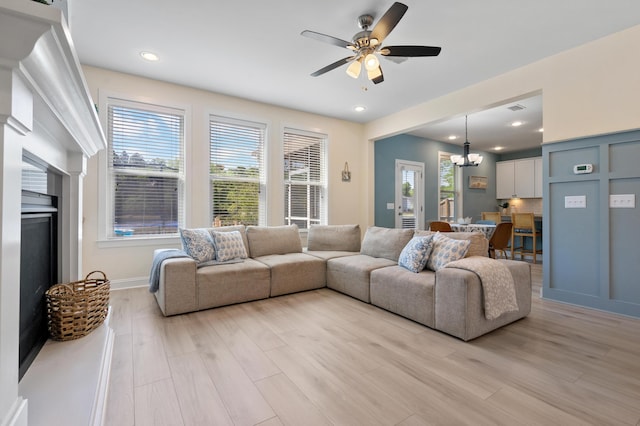 living room featuring ceiling fan with notable chandelier, light wood finished floors, visible vents, and recessed lighting