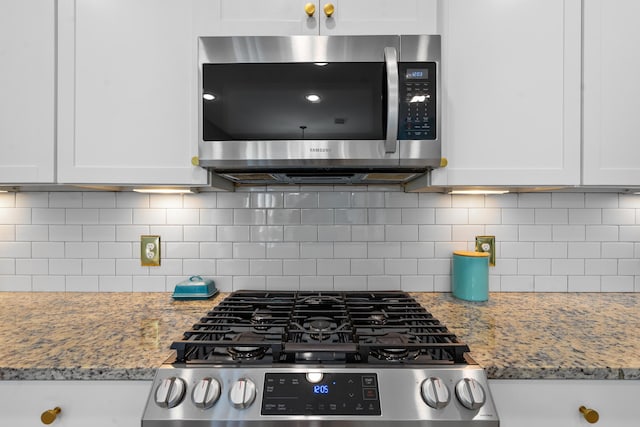 kitchen featuring white cabinets, appliances with stainless steel finishes, decorative backsplash, and light stone counters