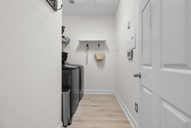 laundry room featuring visible vents, baseboards, laundry area, light wood finished floors, and washer and clothes dryer