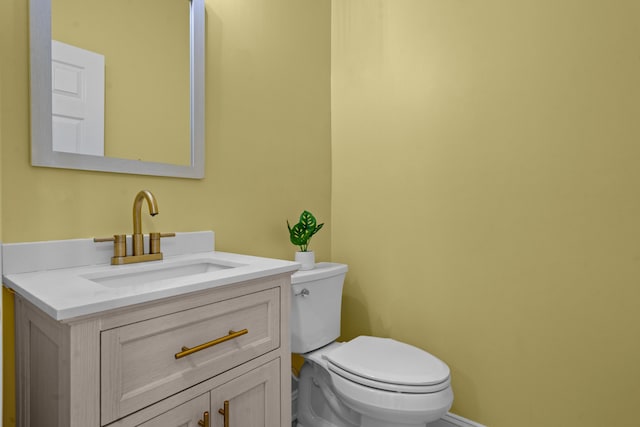 bathroom with toilet, vanity, and baseboards