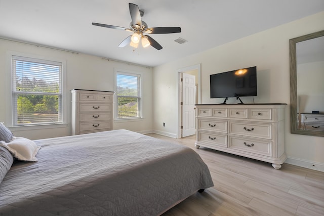bedroom with light wood finished floors, baseboards, a ceiling fan, and visible vents