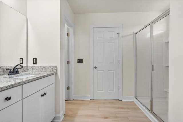 full bathroom featuring vanity, baseboards, a stall shower, and wood finished floors