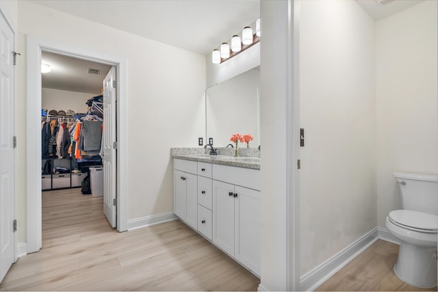 bathroom featuring toilet, wood finished floors, vanity, and baseboards