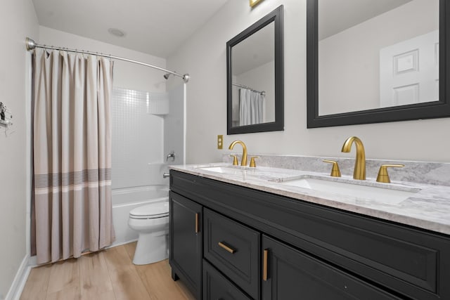 full bathroom with a sink, toilet, double vanity, and wood finished floors