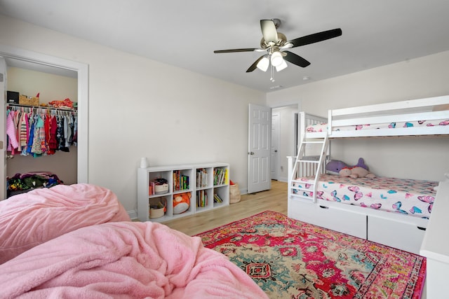 bedroom featuring wood finished floors, a closet, a ceiling fan, and a spacious closet
