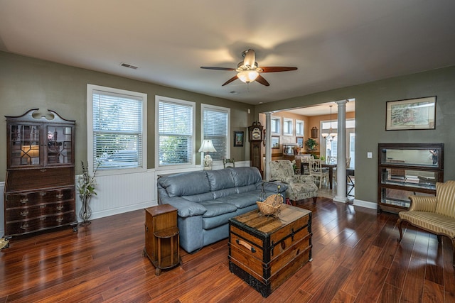 living room featuring a healthy amount of sunlight, ornate columns, ceiling fan, and dark wood-type flooring