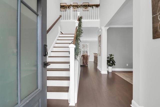 foyer featuring decorative columns, crown molding, and dark hardwood / wood-style flooring