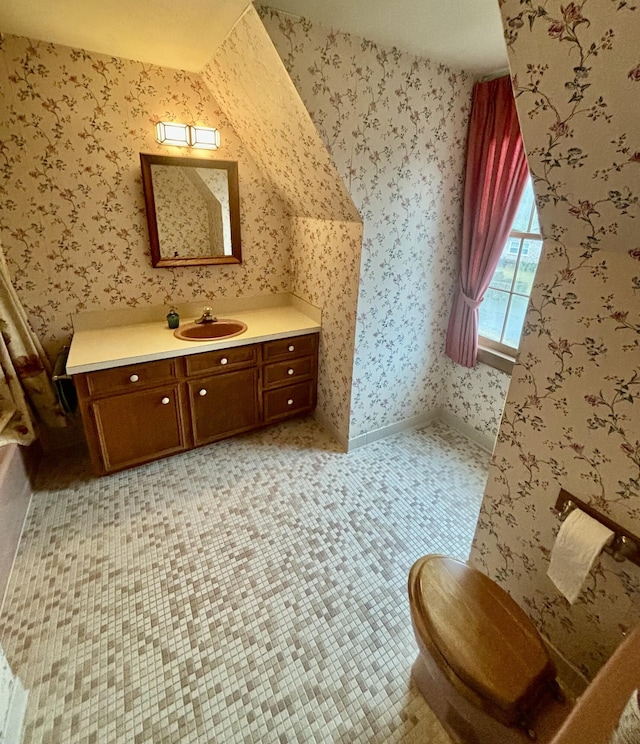 bathroom with tile patterned floors, vanity, toilet, and lofted ceiling