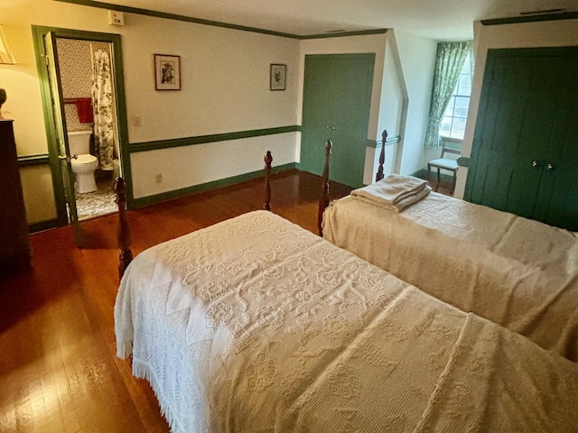 bedroom featuring ensuite bathroom, wood-type flooring, and ornamental molding