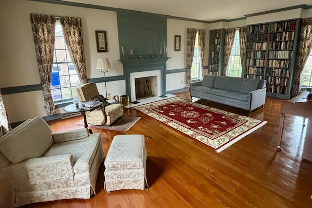 living room with a fireplace, hardwood / wood-style flooring, and ornamental molding