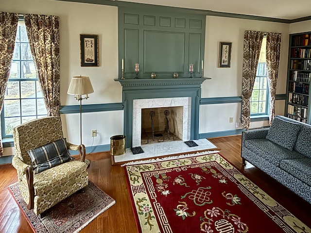 sitting room with dark hardwood / wood-style flooring, ornamental molding, and a premium fireplace