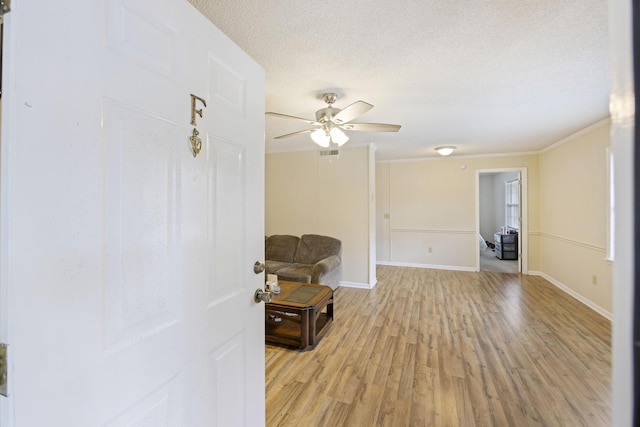 interior space featuring ceiling fan, light hardwood / wood-style floors, crown molding, and a textured ceiling