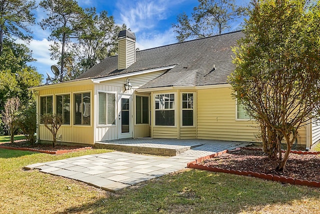 back of property with a lawn, a patio area, and a sunroom