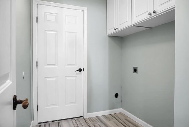 laundry room with hookup for an electric dryer, cabinets, and light wood-type flooring