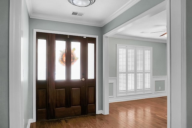 foyer entrance with dark wood-type flooring, ceiling fan, and ornamental molding