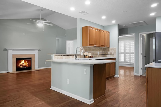 kitchen featuring backsplash, vaulted ceiling, ceiling fan, sink, and dark hardwood / wood-style floors