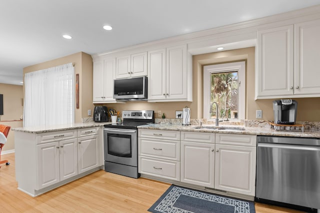 kitchen featuring stainless steel appliances, sink, white cabinets, and light wood-type flooring