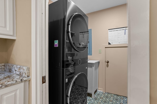 clothes washing area with stacked washer / dryer and cabinets