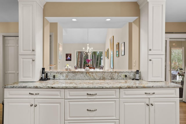 bathroom featuring a notable chandelier, vanity, lofted ceiling, and a wealth of natural light