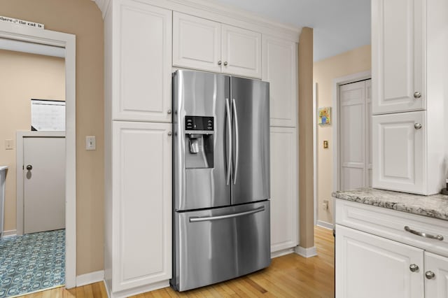 kitchen featuring white cabinetry, light stone countertops, light hardwood / wood-style floors, and stainless steel refrigerator with ice dispenser