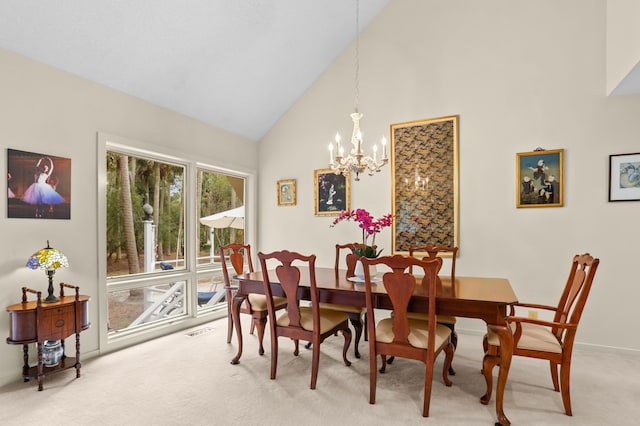 dining area featuring an inviting chandelier, light colored carpet, and high vaulted ceiling