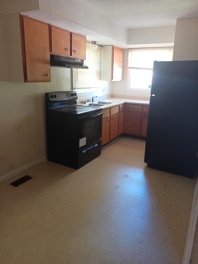 kitchen featuring black appliances, brown cabinetry, a sink, and under cabinet range hood