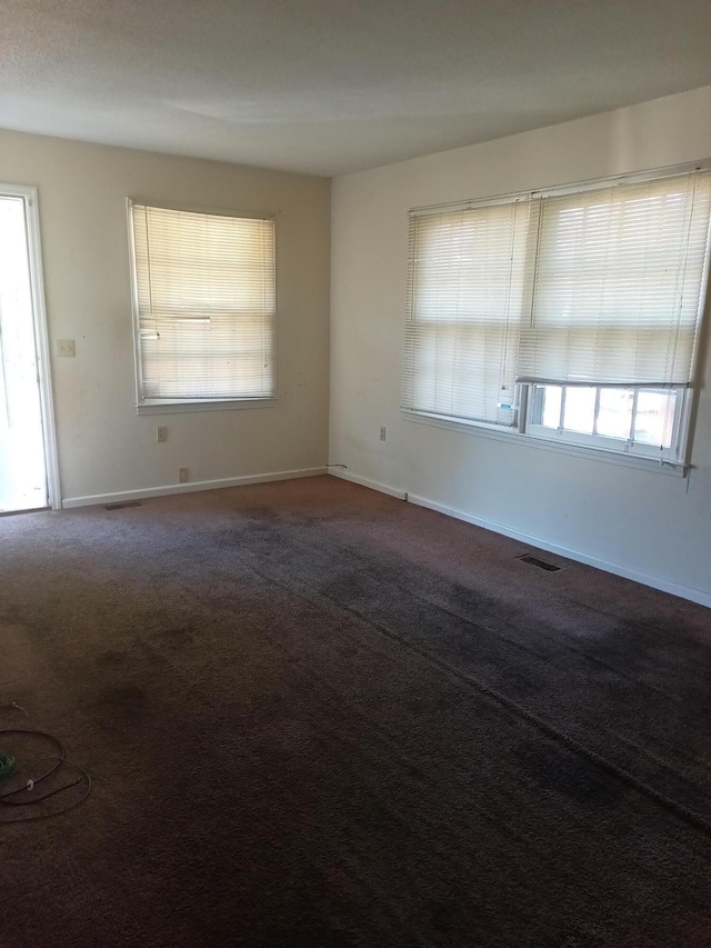 carpeted spare room featuring visible vents and baseboards