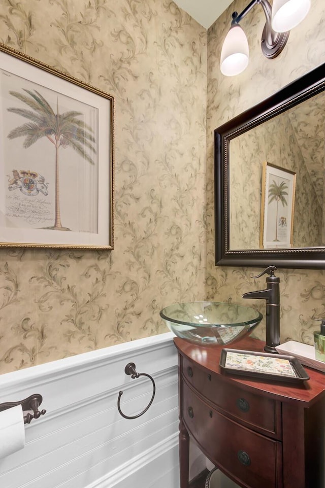 bathroom with wainscoting, vanity, and wallpapered walls