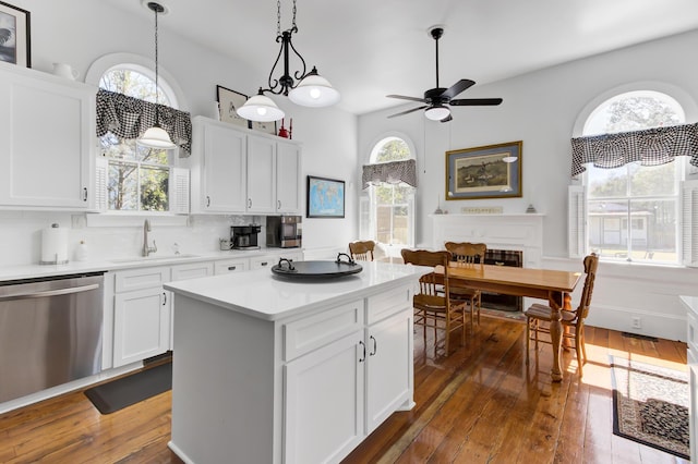 kitchen featuring dark wood finished floors, dishwasher, light countertops, decorative backsplash, and a sink