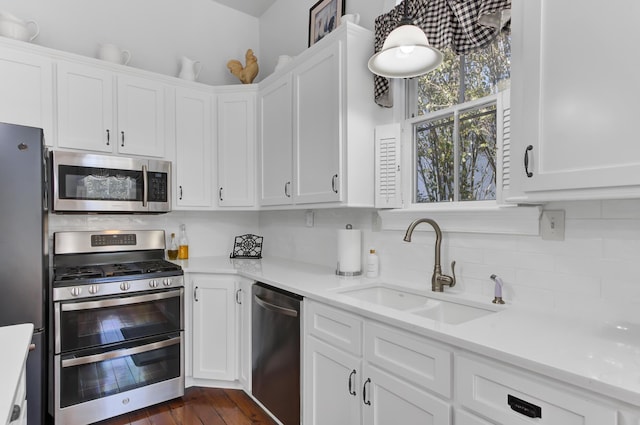 kitchen with a sink, appliances with stainless steel finishes, light countertops, and white cabinetry