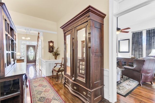 foyer with a wainscoted wall, ceiling fan with notable chandelier, a decorative wall, and hardwood / wood-style flooring