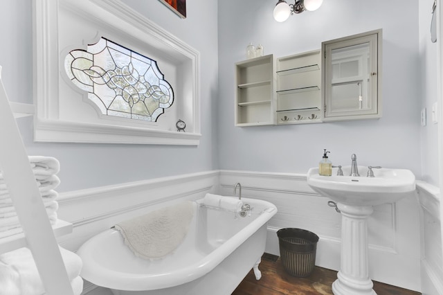 bathroom with a soaking tub, wood finished floors, and wainscoting